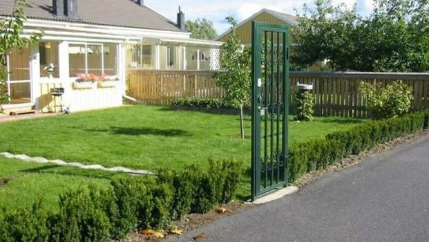 Strong metal gate surrounded by a thick hedge that doesn't even reach knee height, easily stepped over