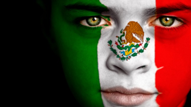 Portrait of a concerned boy with the flag of Mexico painted on his face